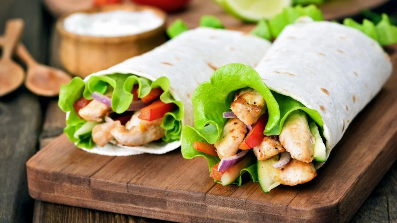 Los wraps o tortillas rellenas son una opción rápida y versátil. Solo necesitas tortillas integrales, pechuga de pollo cocida, lechuga, jitomate y un poco de queso bajo en grasa.